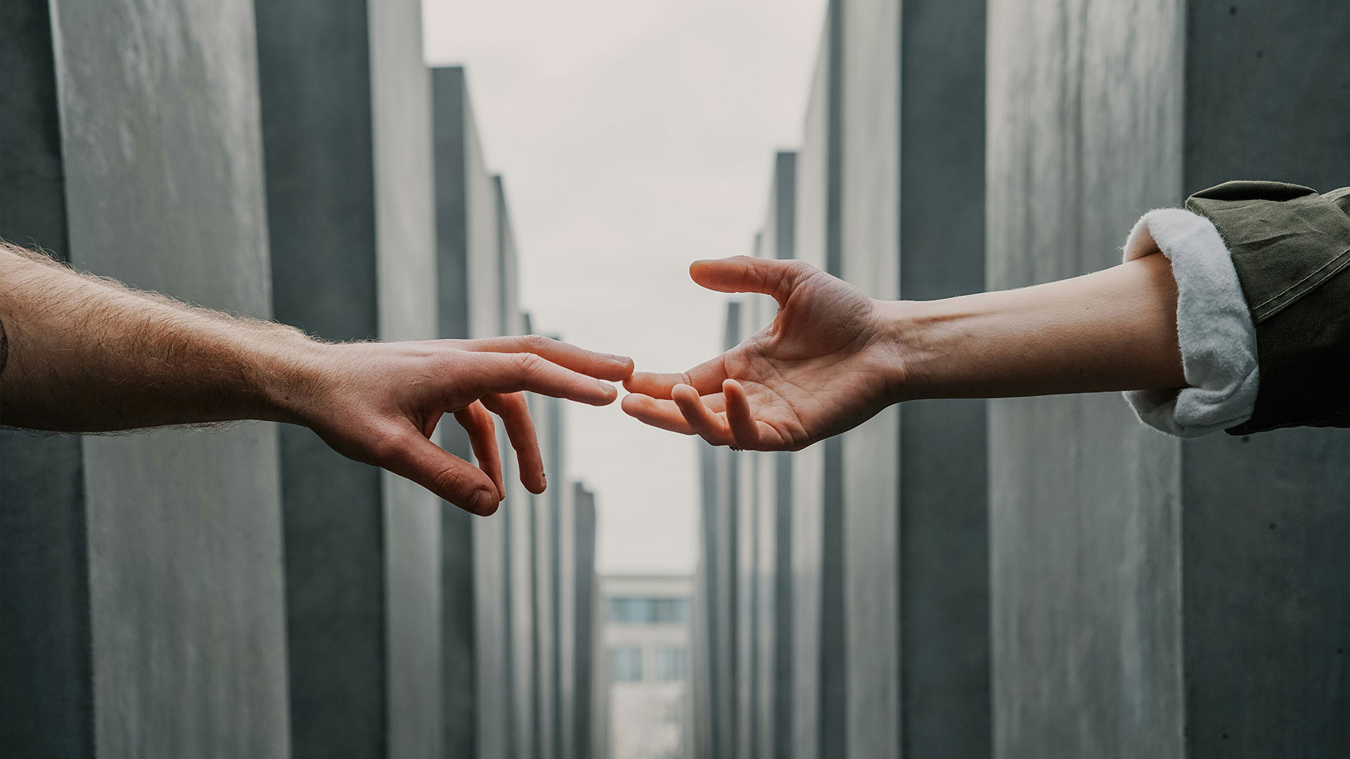 Two hands reaching out to connect against a backdrop of modern architecture