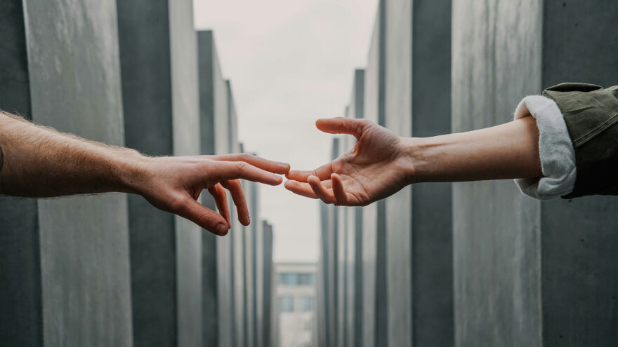 Two hands reaching out to connect against a backdrop of modern architecture